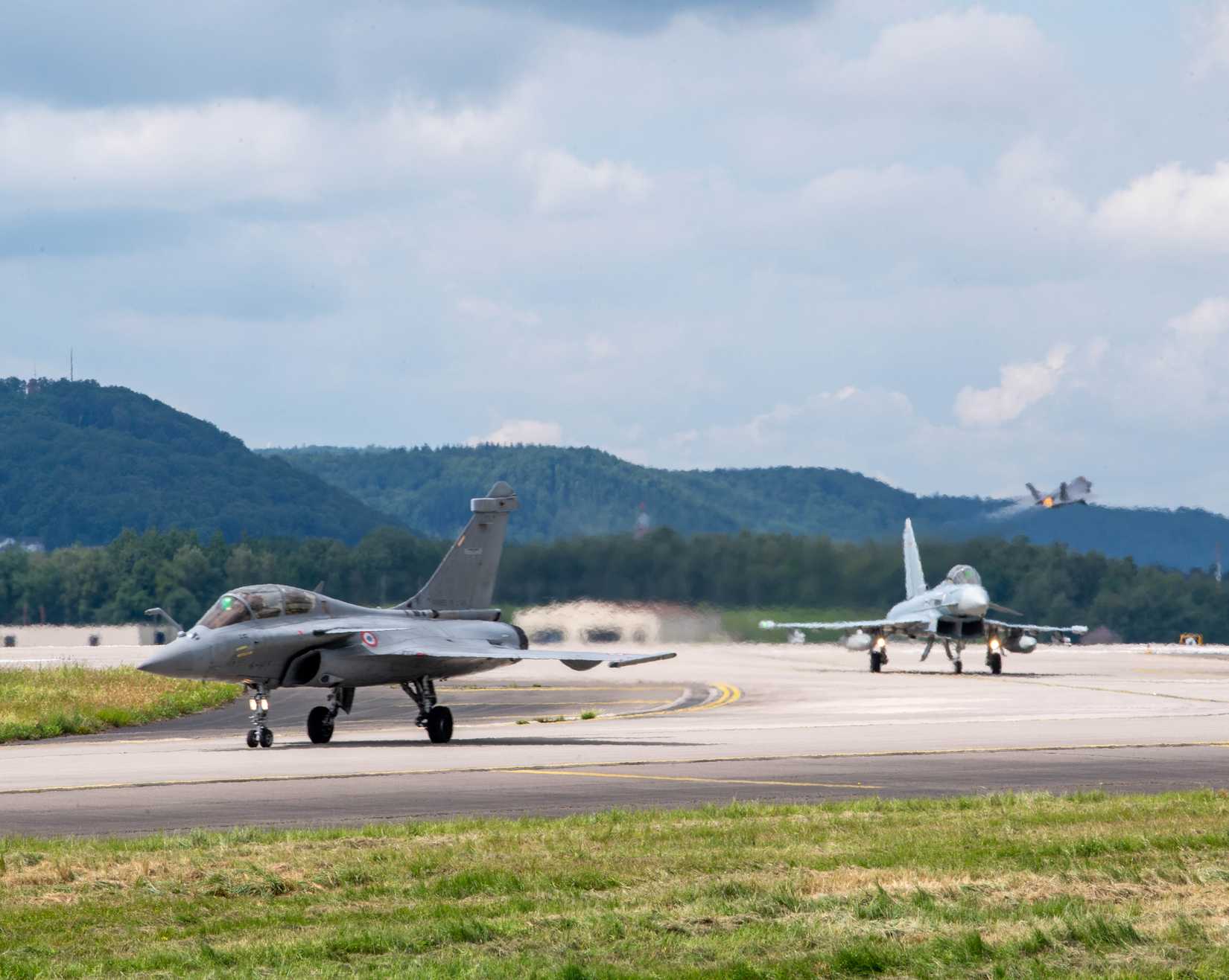 A French air force Dassault Rafale C, and a Eurofighter Typhoon taxi as an F-35A Lightning II takes off at Ramstein Air Base, Germany, June 6, 2024.