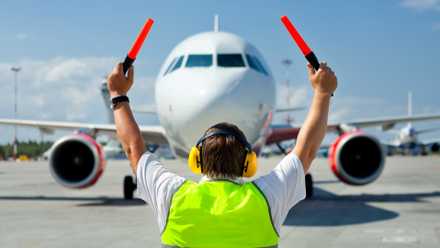 A ground crew marshalling an aircraft into its parking spot at an airport