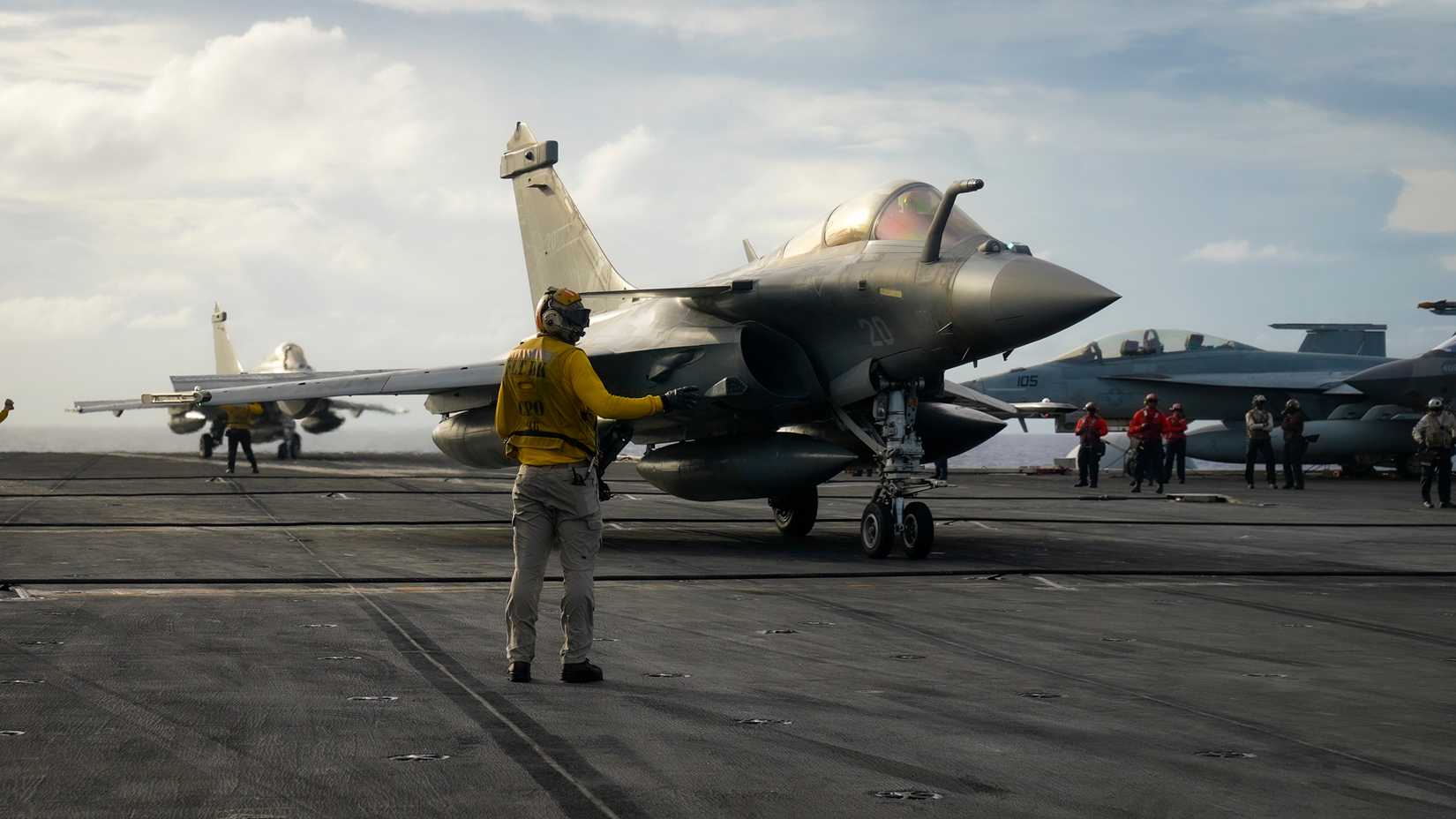 A Sailor directs a Rafale Marine F4 fighter jet, assigned to the aircraft carrier FS Charles De Gaulle.