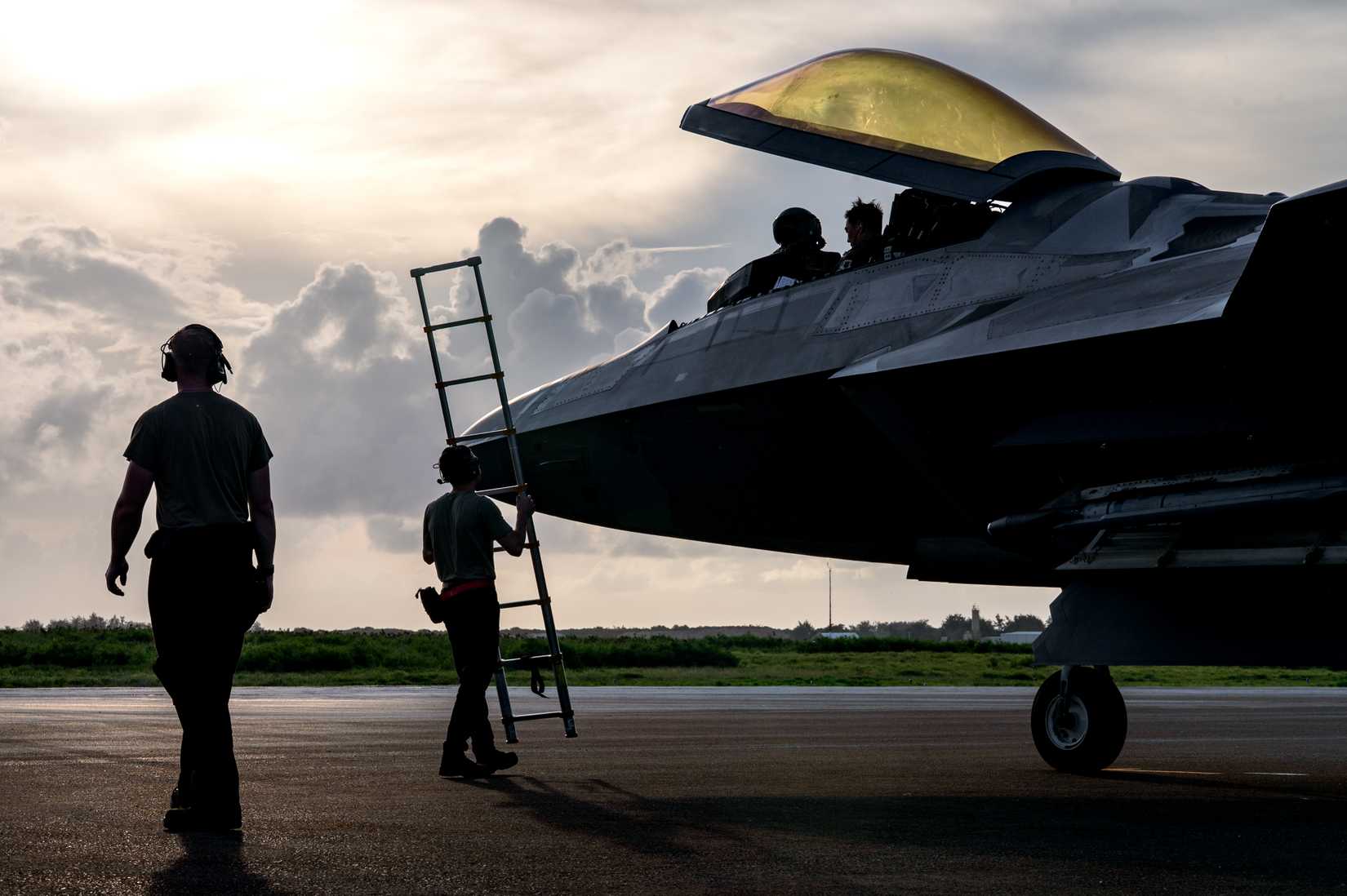 Air Force Senior Airman Dylan Gurski and Oliver Budd, crew chiefs, assist an F-22 Raptor pilot in disembarking from the cockpit.