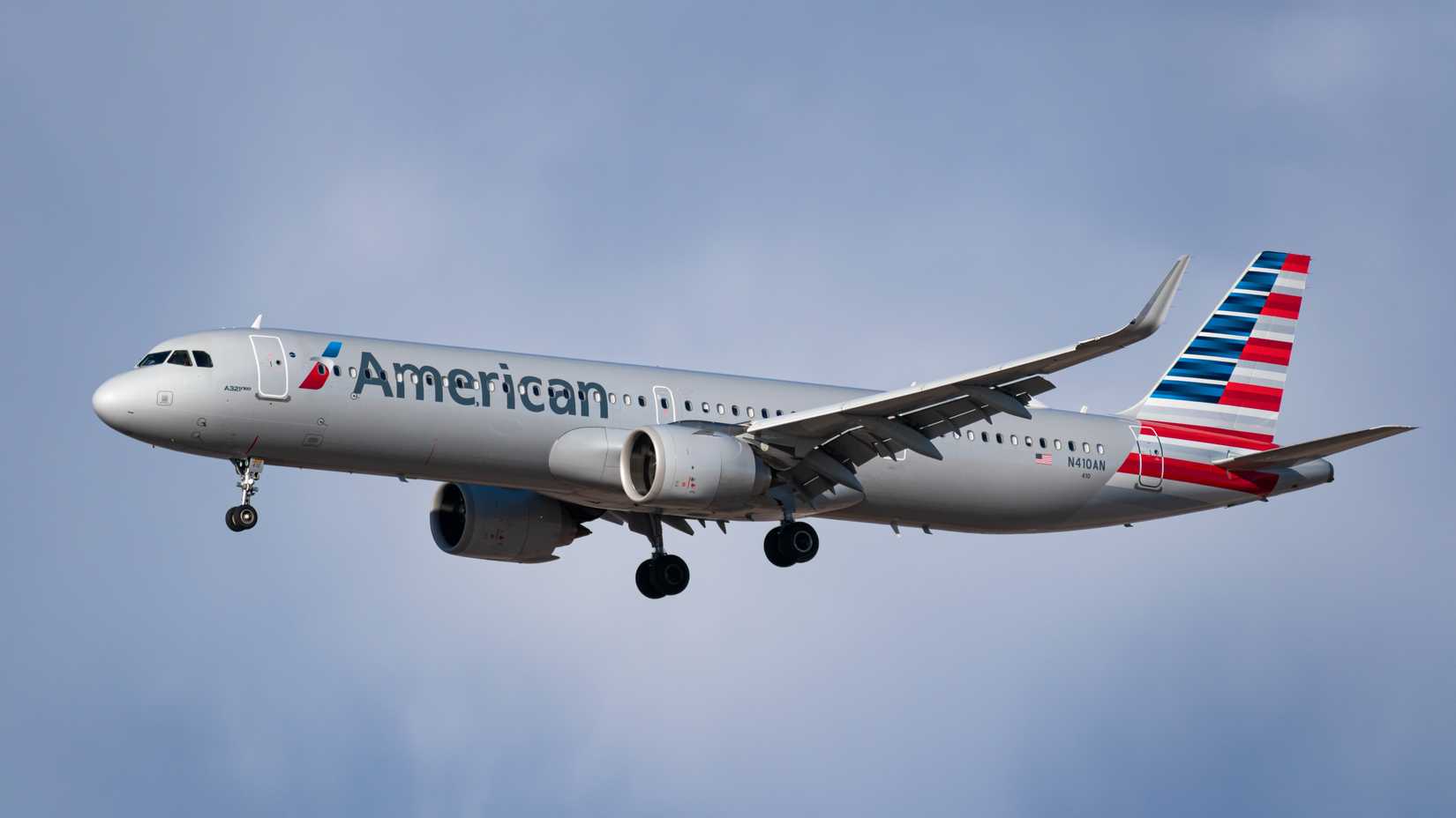American Airlines A321neo flying across cloudy skies