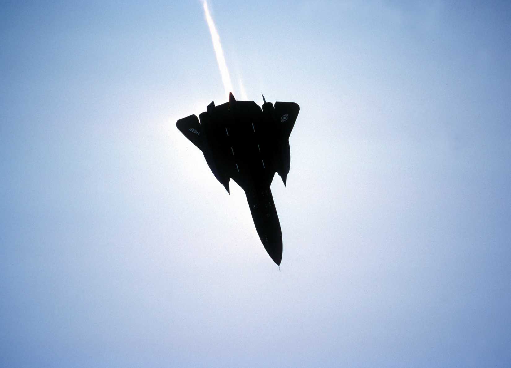 An SR-71 Black Bird reconnaissance aircraft, with afterburner on, flies overhead. Exact Date Shot Unknown.