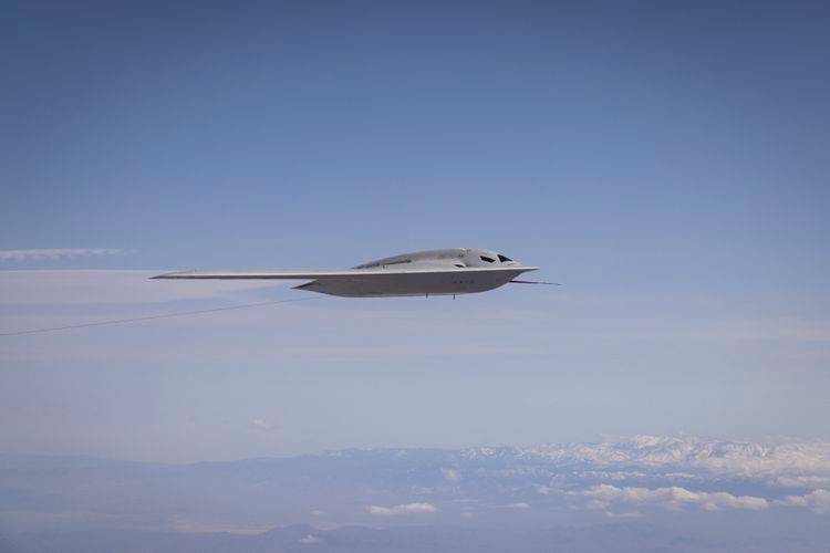 sideways view of B-21 flying across sky over clouds