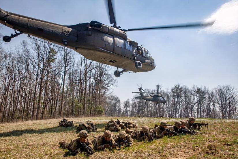 Blackhawk helicopter is hovering above soldiers it just dropped off. 