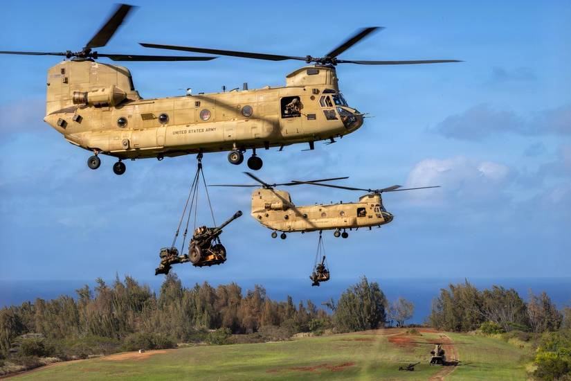 Two CH-47's carrying artillery