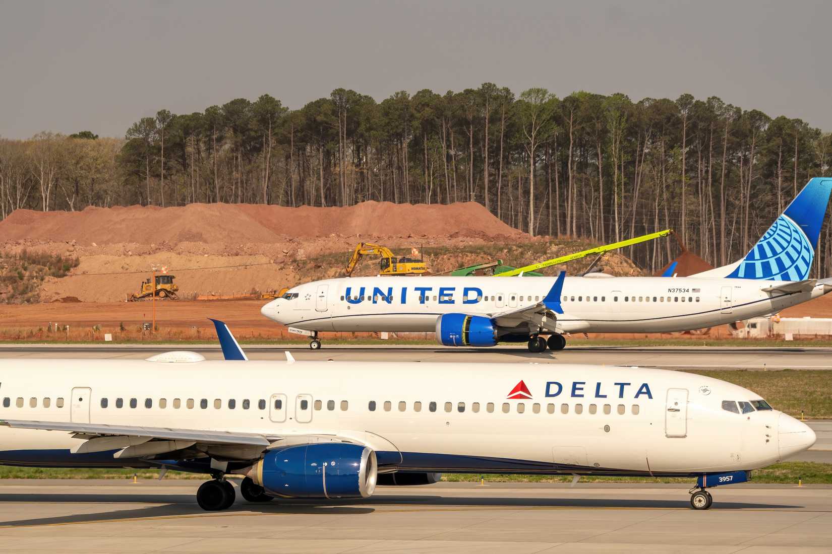 Delta Air Lines and United Airlines passenger aircraft taxi on the runway at RDU Airport.