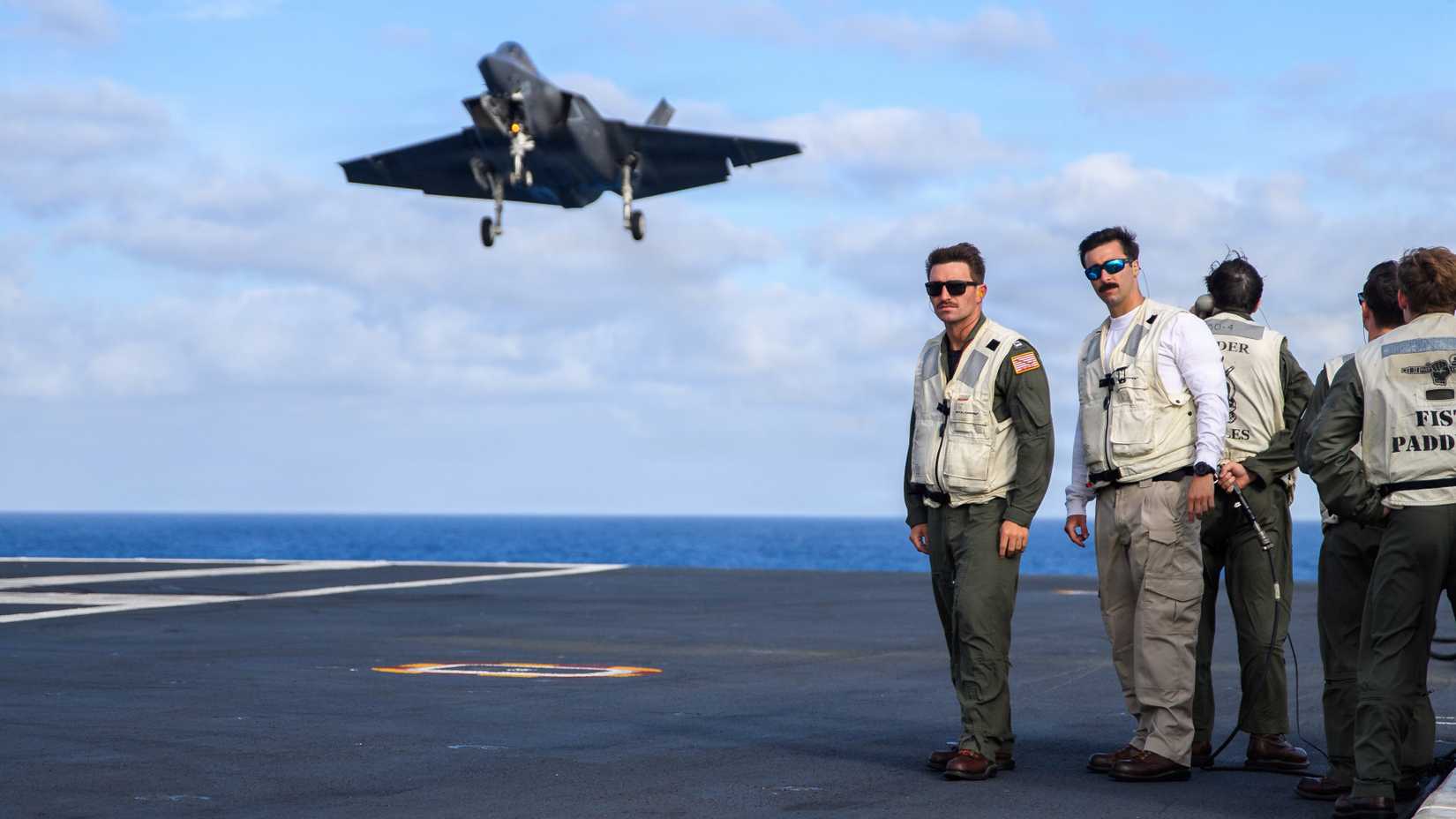 landing Signals Officers under a F-35C Lightning II, assigned to Strike Fighter Squadron (VFA) 86, as it approaches to land on the flight deck of Nimitz-class aircraft carrier USS Theodore Roosevelt (CVN 71),