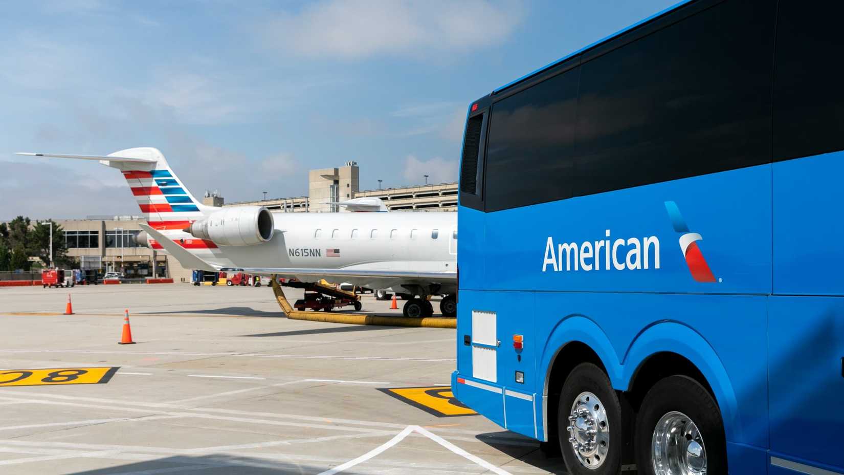 Landline bus on tarmac by American Airlines regional jet.
