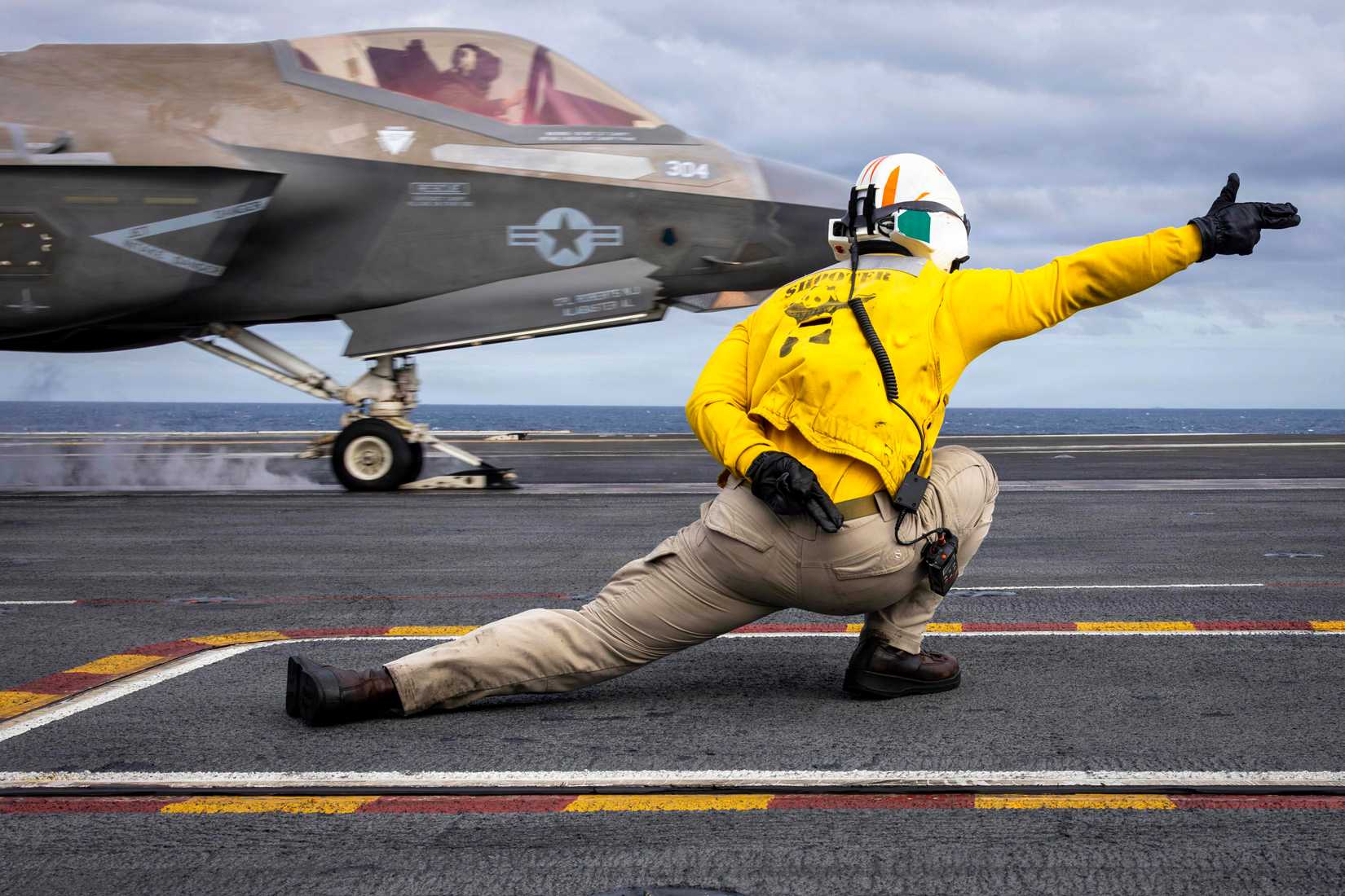 Navy Lt. Cmdr. Jarrett Walden signals an F-35C Lightning II, attached to Marine Fighter Attack Squadron (VMFA) 314, as it launches from the flight deck