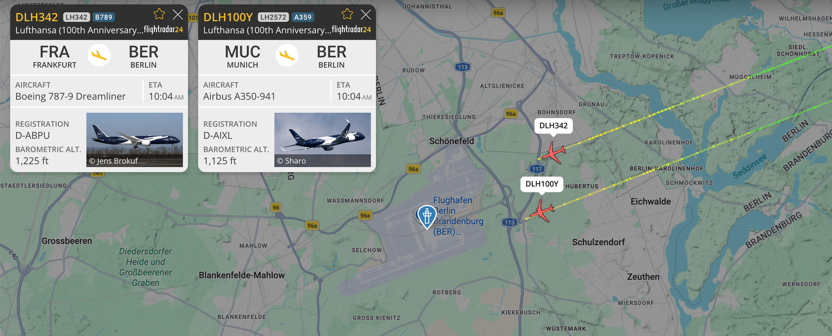 A flight tracking map from Flightradar24 shows two Lufthansa aircraft, flight DLH342 (a Boeing 787-9 Dreamliner) and flight DLH100Y (an Airbus A350-941), on their final approach to Berlin Brandenburg Airport (BER). Both aircraft are sporting Lufthansa's "100th Anniversary" livery and are shown at low altitudes of approximately 1,200 feet as they parallel each other toward the runways.