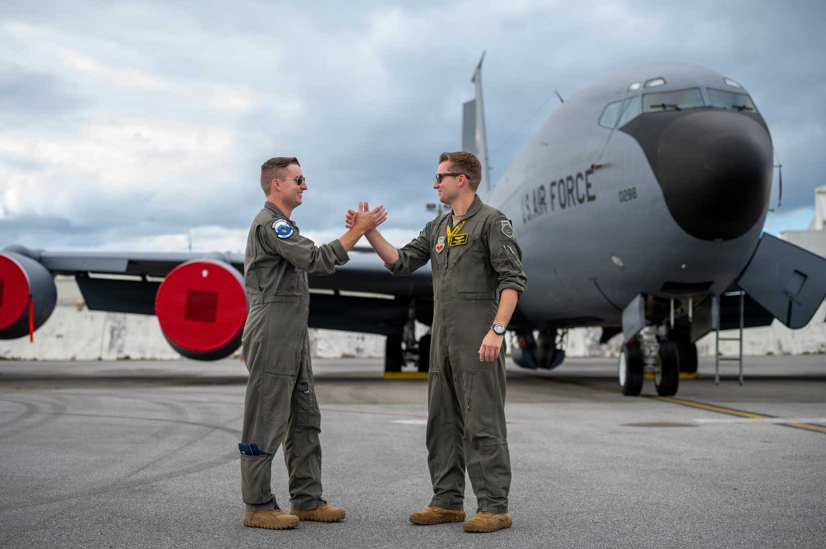 Twins and Air Force Captains Jordan and Jared Wesemann deployed to Kadena Air Base, handshake in front of a KC-135 Stratotanker.