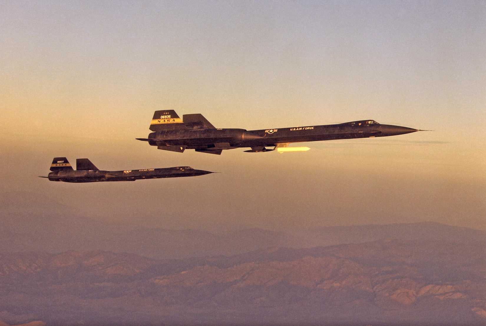 YF-12A 60-6935 carries the ''coldwall'' heat transfer pod on a pylon beneath the forward fuselage. In the background, the YF-12C flies photo chase.