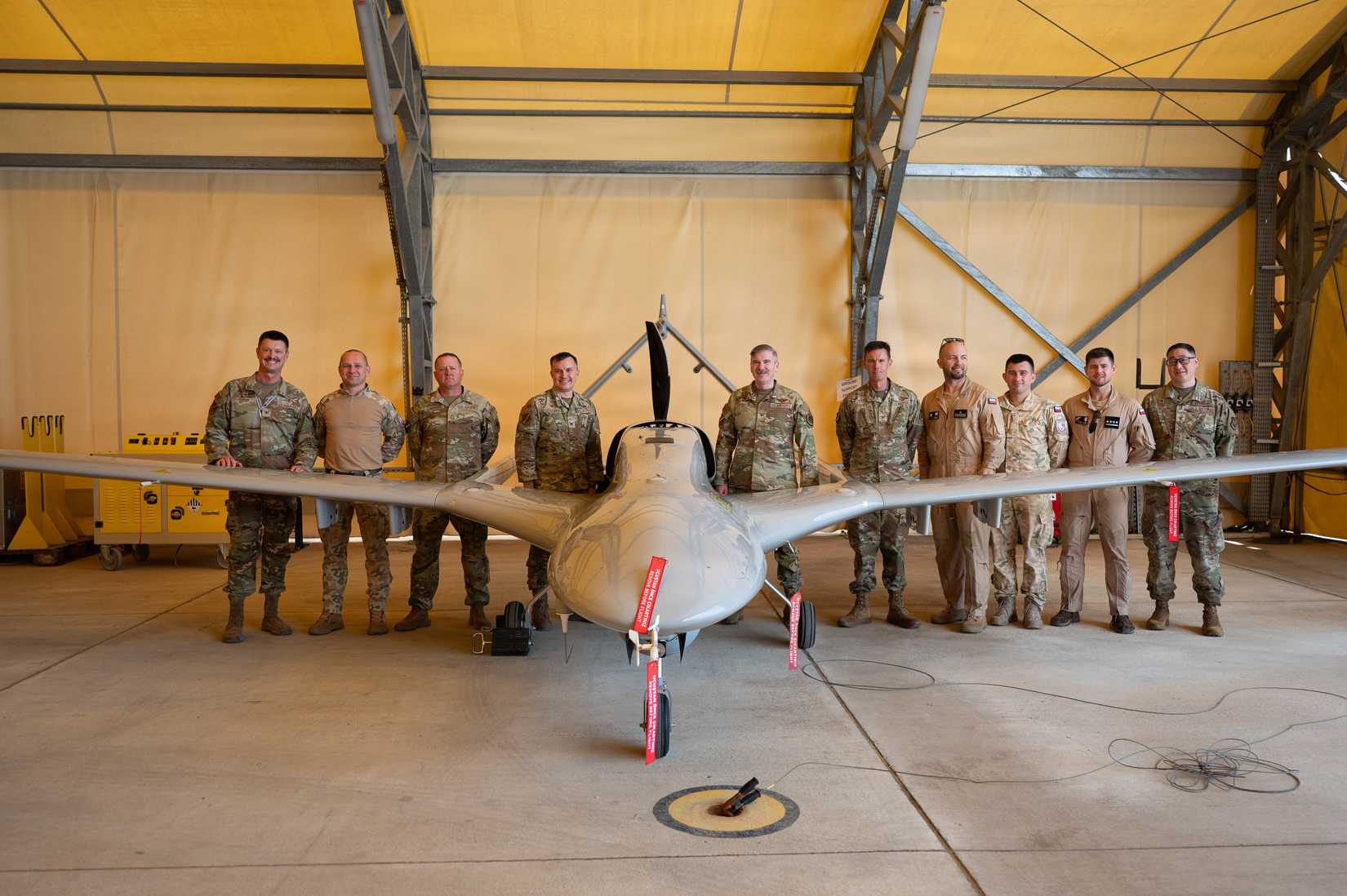 39th Air Base Wing senior leaders and Polish Military Contingent service members pose for a group photo in front of a Bayraktar TB2 Unmanned Aerial Vehicle (UAV).