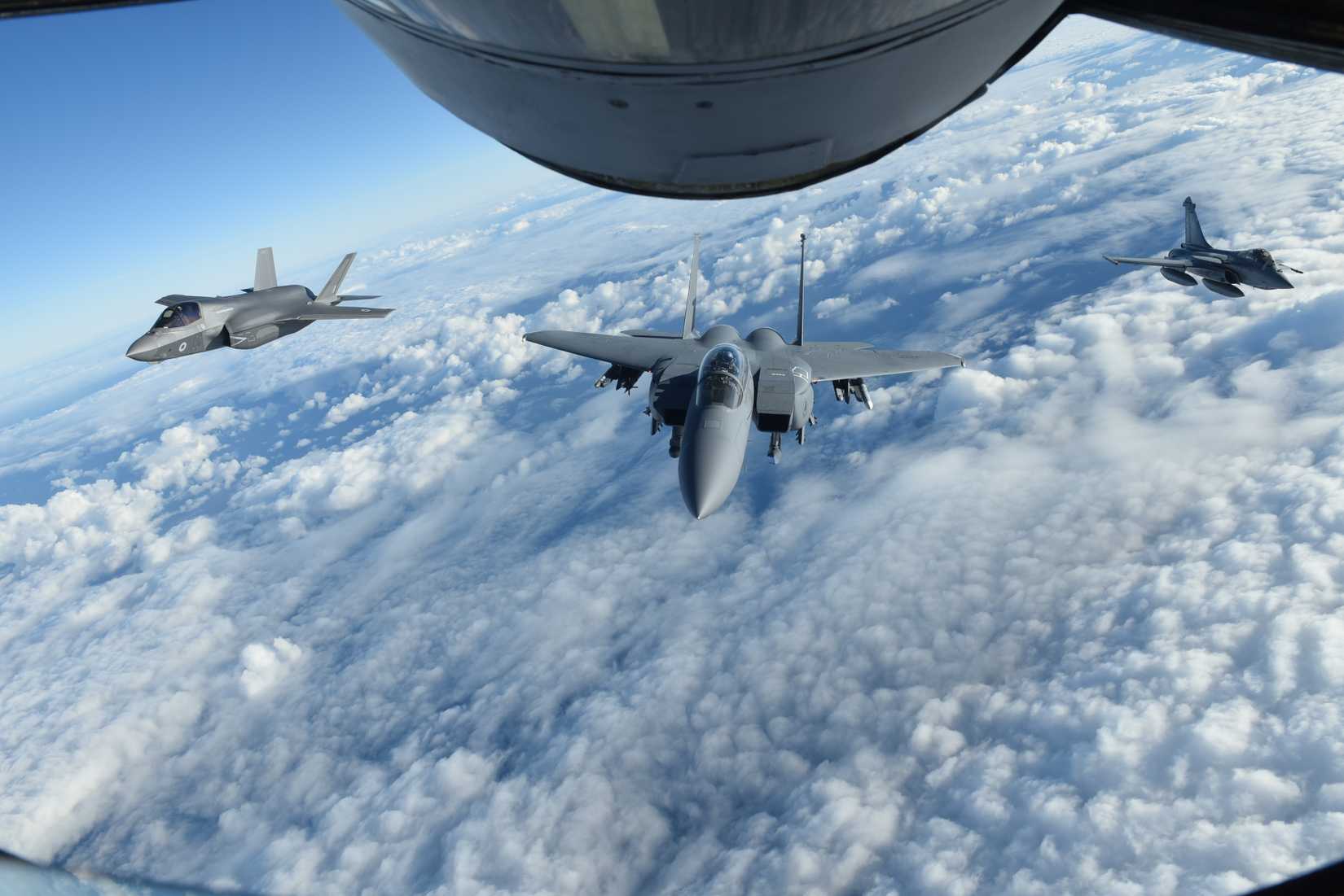 A Royal Air Force F-35 Lightning II aircraft, left, U.S. Air Force F-15E Strike Eagle, center, and French air force Dassault Rafale fly behind a U.S. Air Force KC-135 Stratotanker.