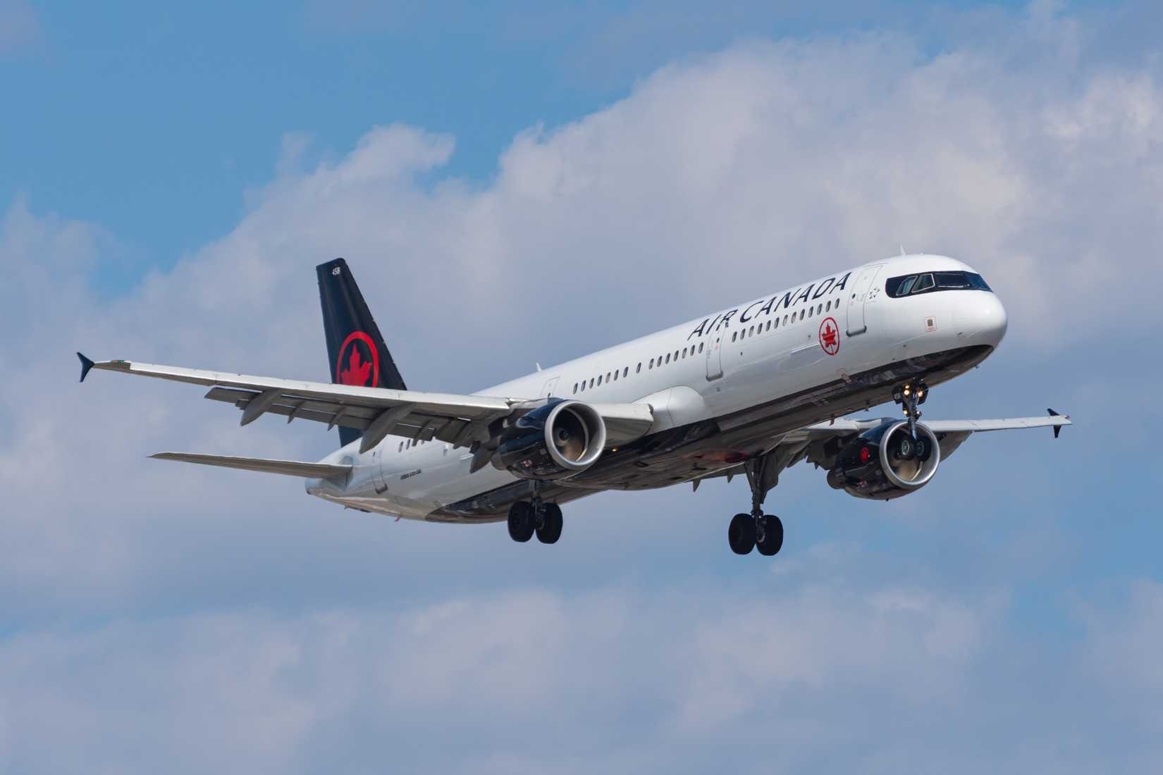 Air Canada A321 flying across cloudy skies