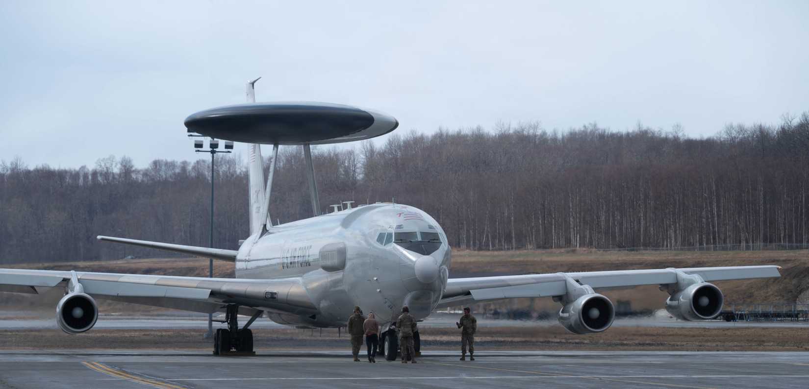 Air Force Airmen from the 718th Aircraft Maintenance Squadron assist an E-3 Sentry taxiing prior to take-off during exercise Red Flag Alaska 26-1.