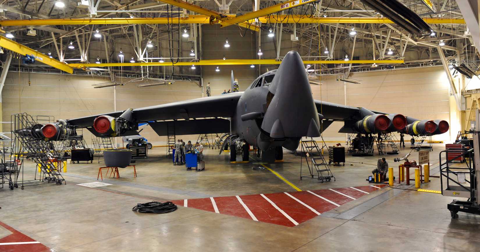 A B-52 sits in a repair bay or hangar undergoing inspections or repair.