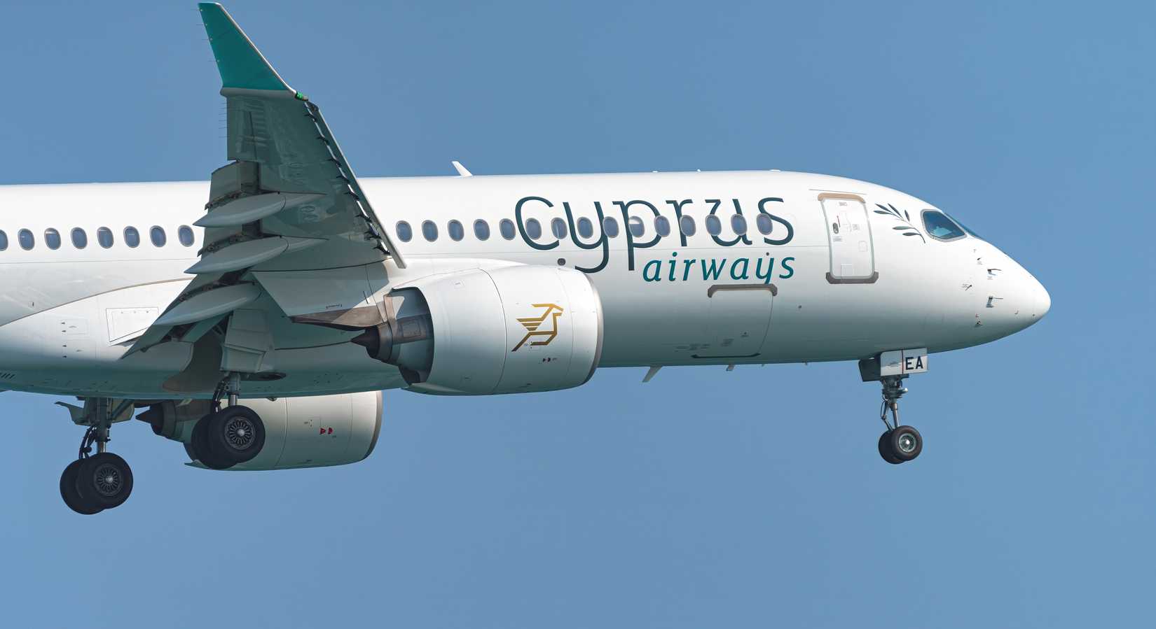 Cyprus Airways passenger jet flying with landing gear extended against a clear blue sky.