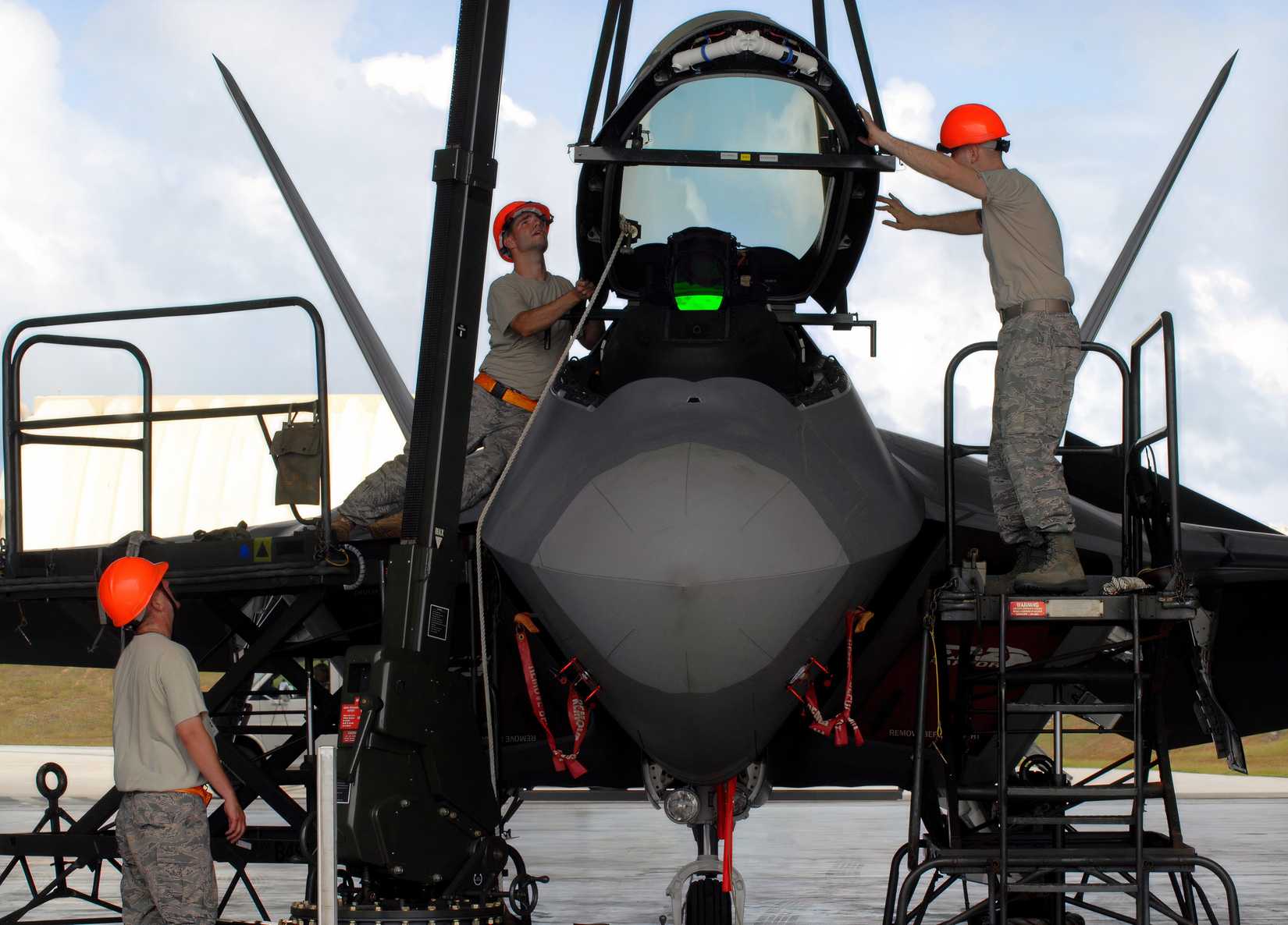 A crew is performing maintenance on an F-22