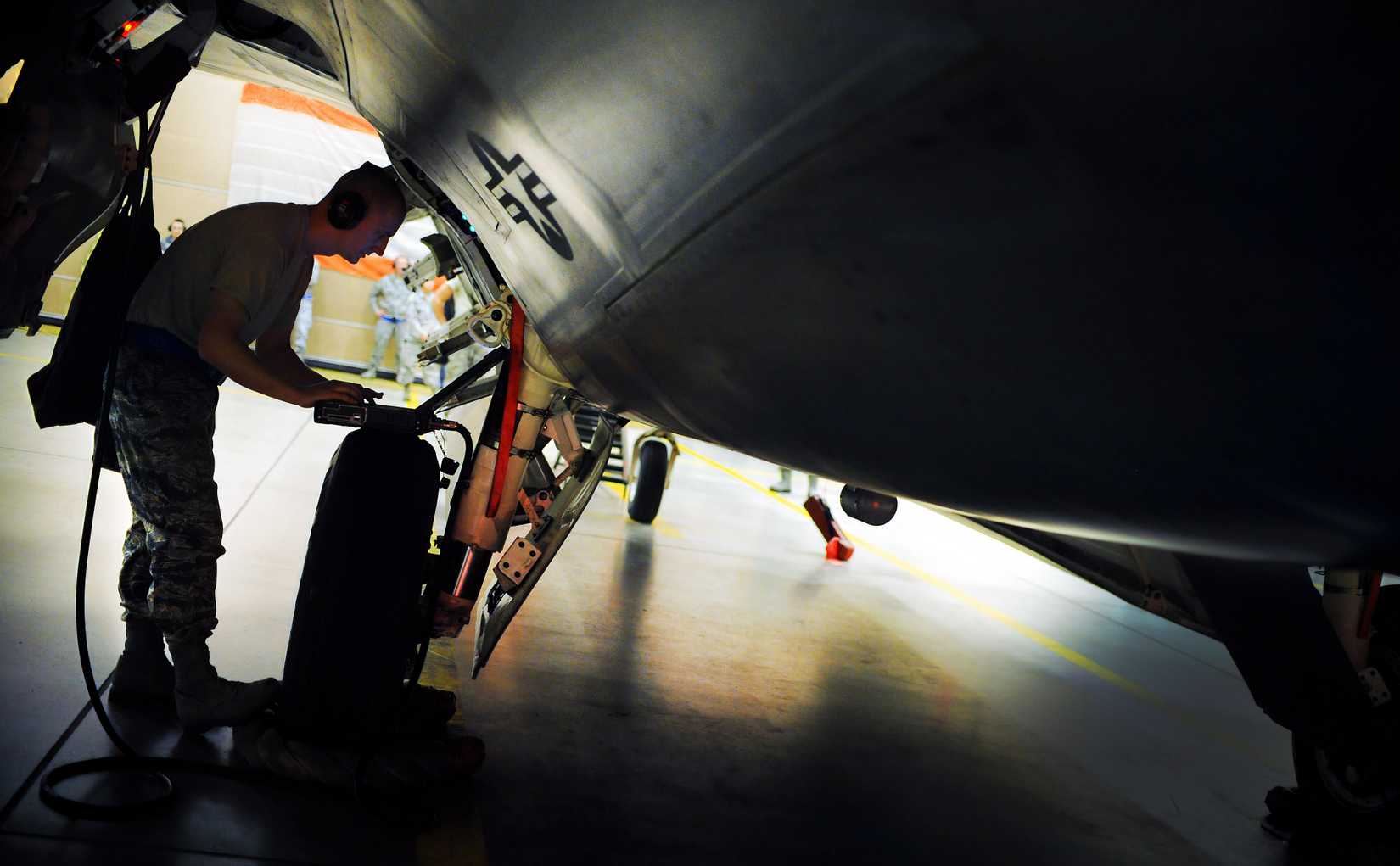 Maintainer looking at the wheel-well of an F-22