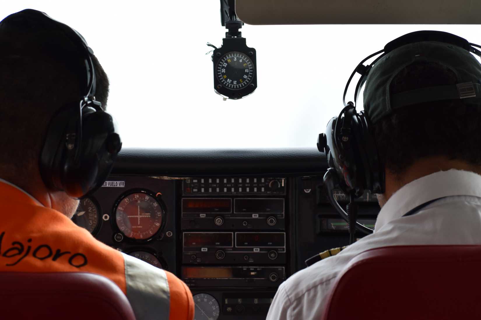Pilots in cockpit with orange hi vis vest