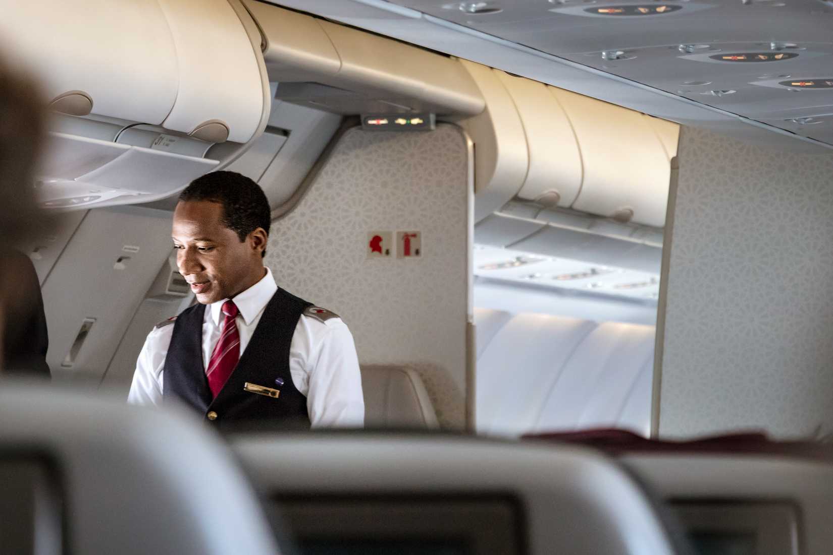male flight attendant speaking with passenger Qatar Airways