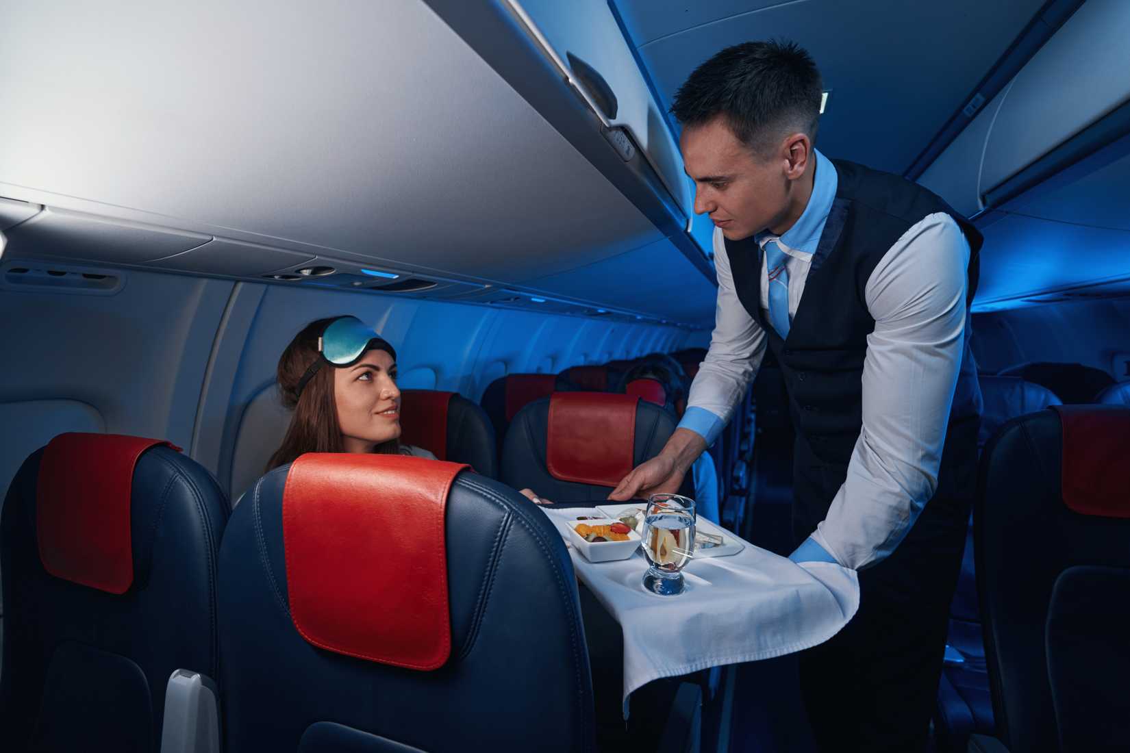male flight attendant serving meal to passenger