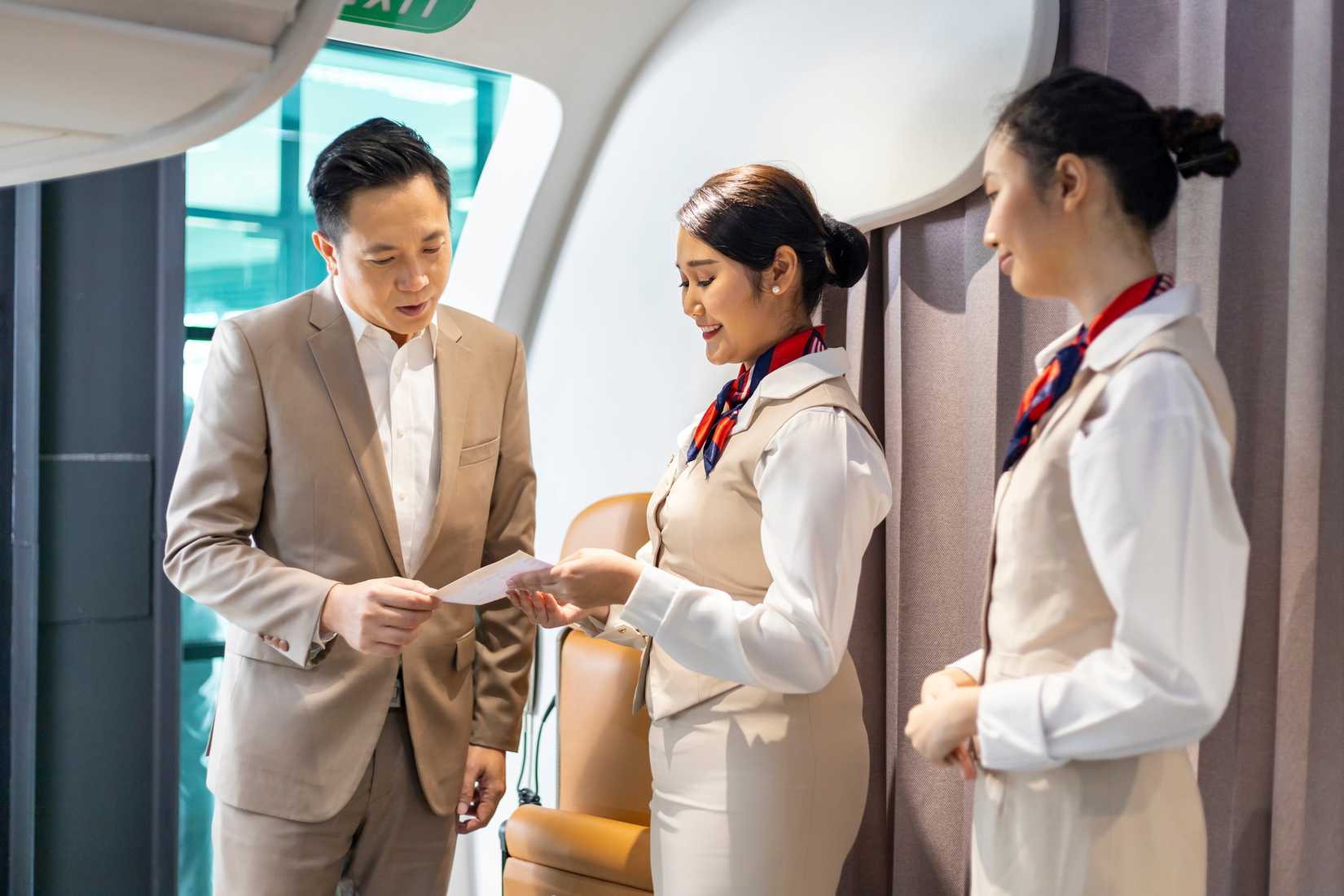 Flight attendants welcoming a passenger, checking their boarding pass 