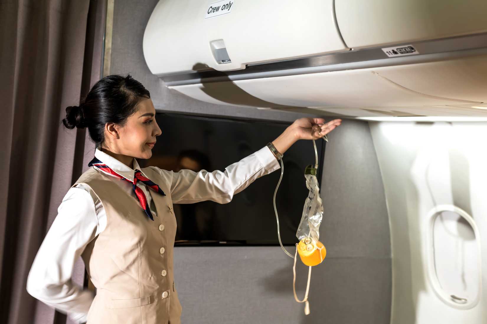 cabin crew performing safety demo with oxygen mask
