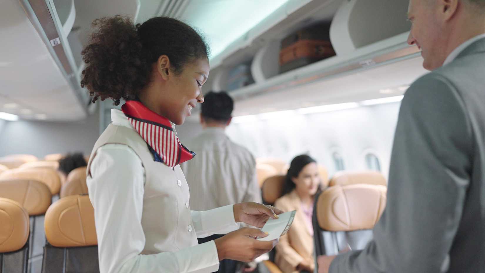 Flight attendant checking passenger's boarding pass on the aircraft 