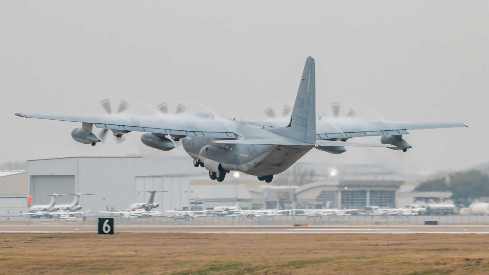Austin, Texas, January 28, 2023 Austin-Bergstrom International Airport: USAF C-130 Taking off Runway 18L in Rainy or Cloudy Conditions with some passenger aircraft in the background