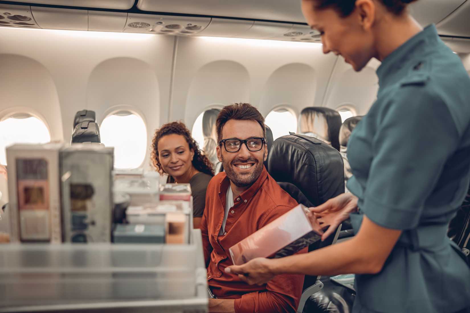 Friendly passengers engaging with a flight attendant during inflight meal services  