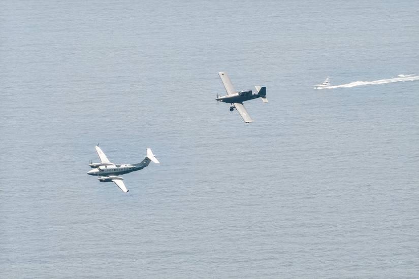 A Skyraider II tailing another aircraft over a body of water.