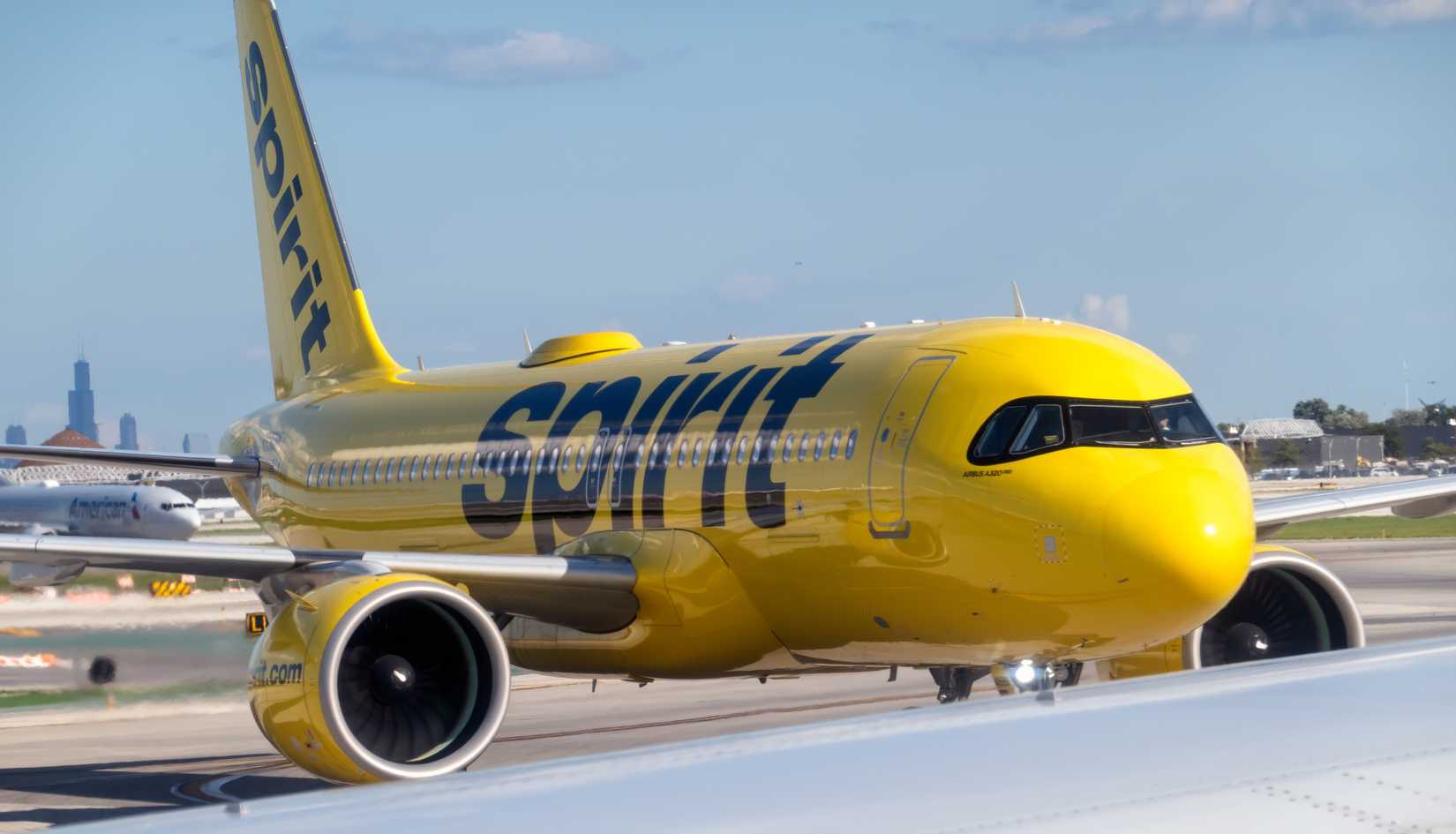 Spirit Airlines Airbus A320neo taxis at O'Hare International Airport on a clear sunny day.