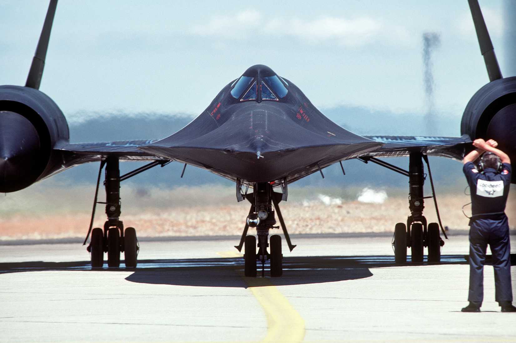A ground crewman signals an SR-71A strategic reconnaissance aircraft preparing for takeoff.