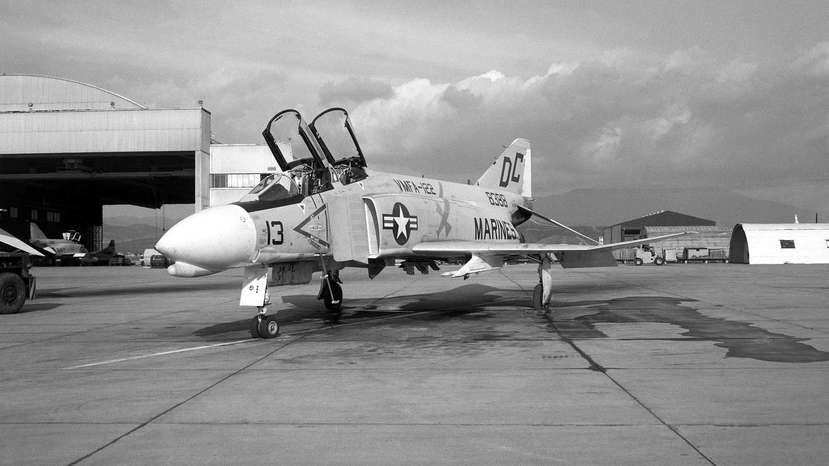 A left front view of an F-4B Phantom II aircraft on the flight line. The aircraft is assigned to Marine Fighter Attack Squadron 122 (VMFA-122).