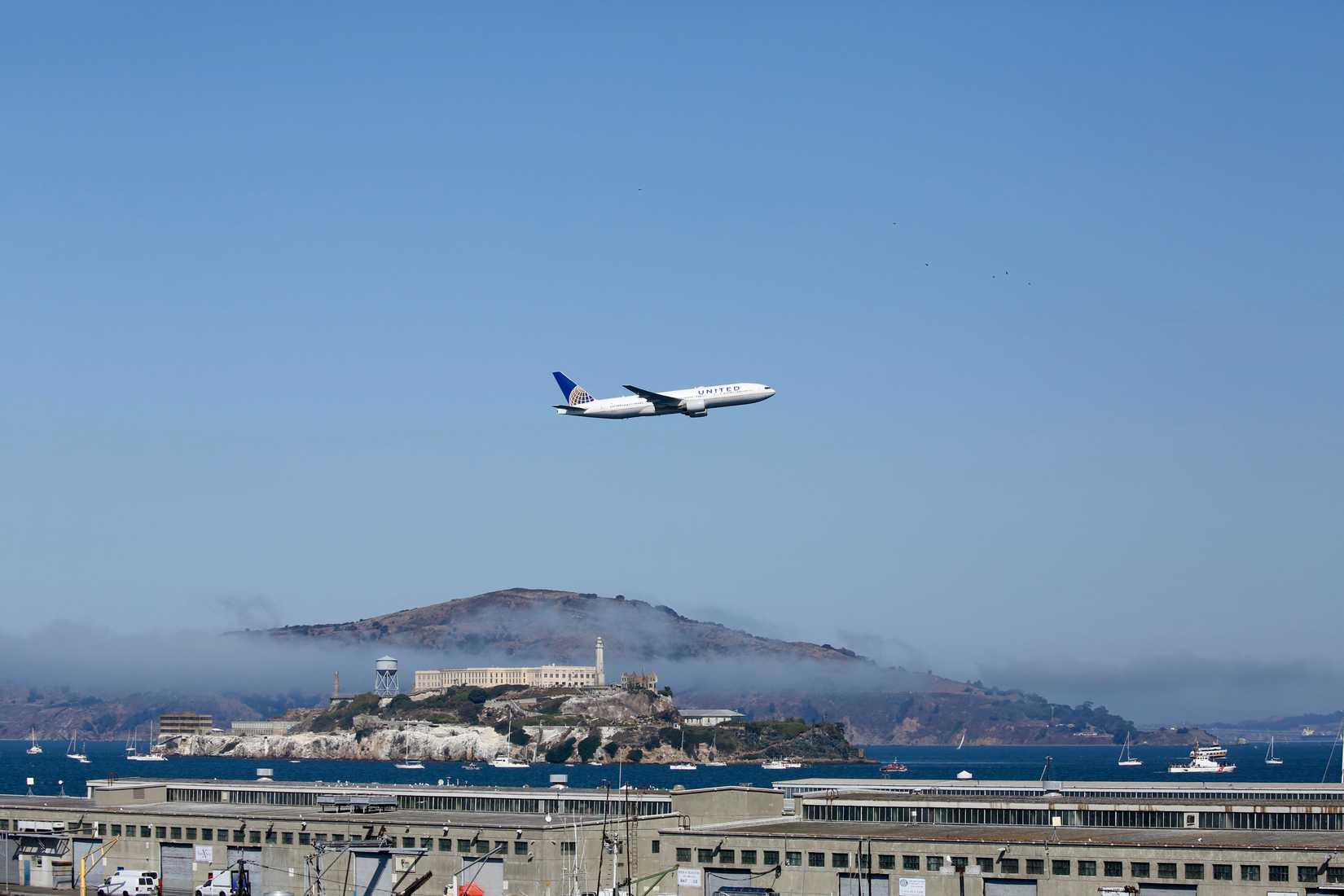A United Airlines 777 flies over the bay in San Francisco with San Quentin prison in the background during Fleet Week.
