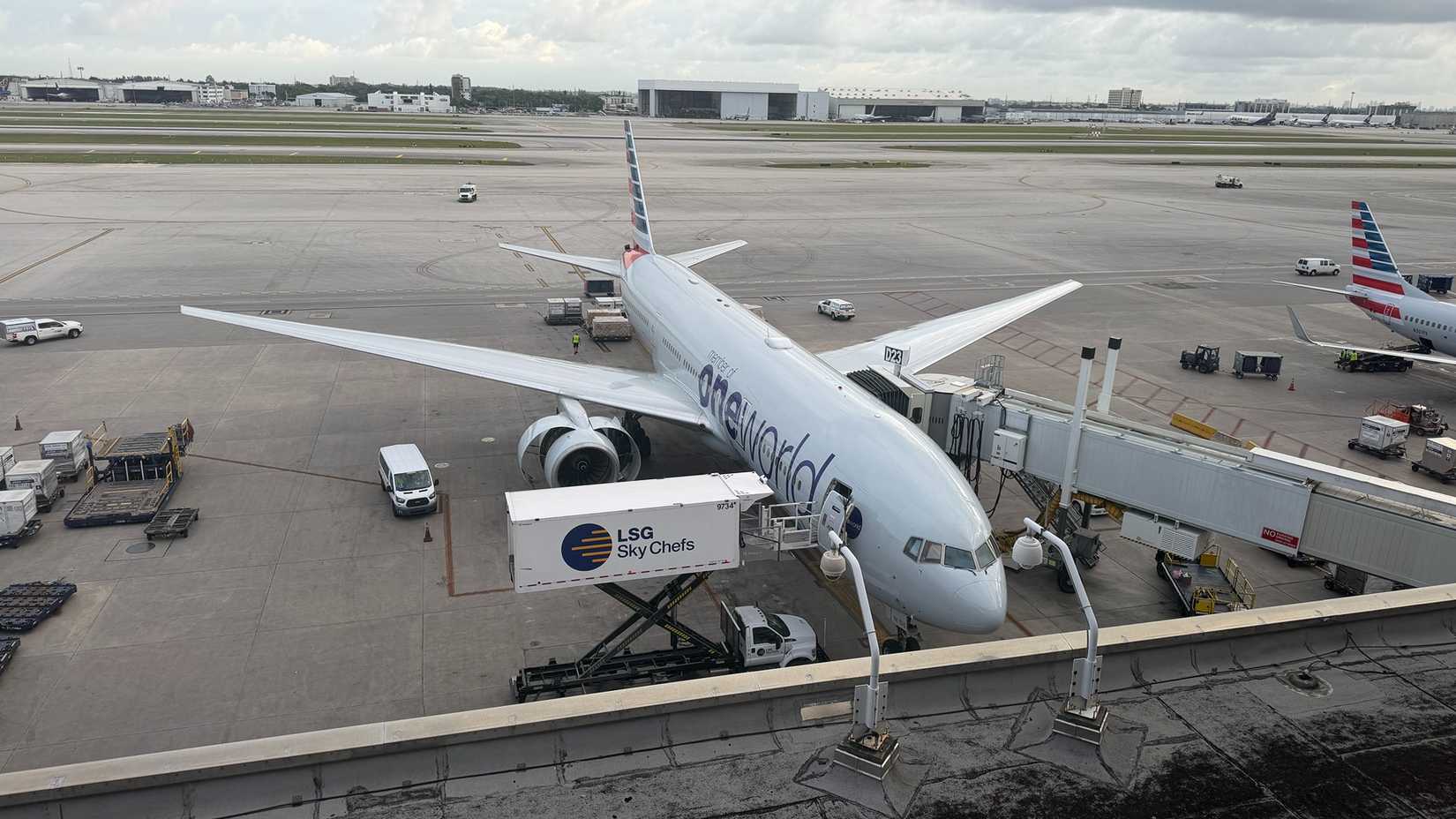 An American Airlines 777-200ER is serviced at a jet bridge.