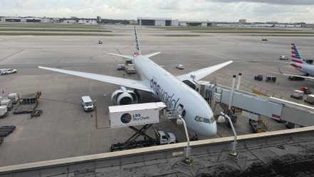 An American Airlines 777-200ER is serviced at a jet bridge.