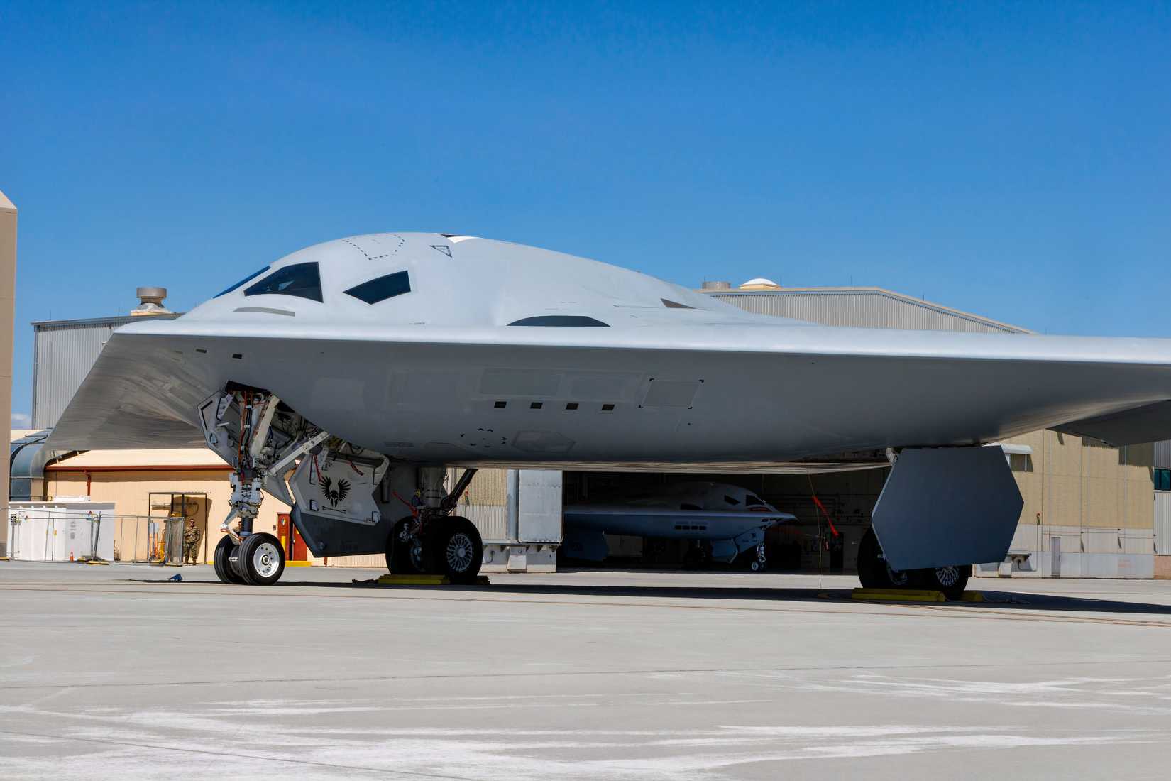 A photo of a B-21 Raider parked on an apron near a hangar at Edwards AFB.