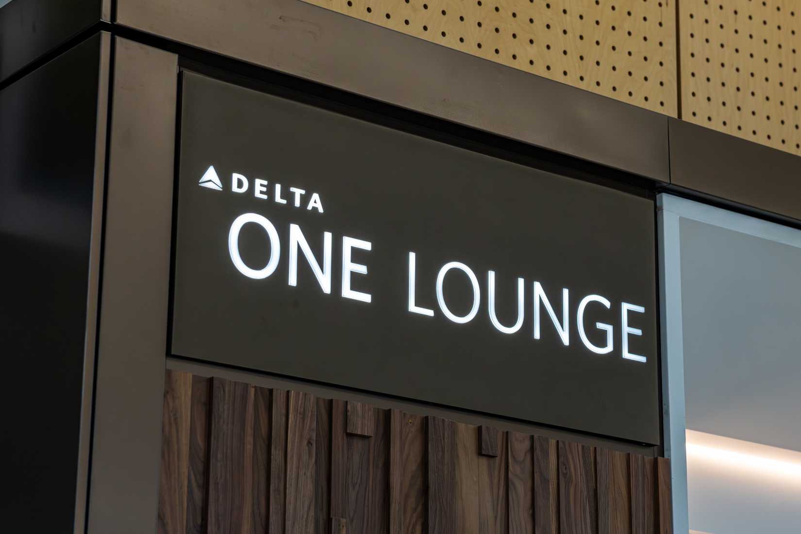  Delta One Lounge illuminated entrance sign with wood paneling at Seattle-Tacoma International Airport