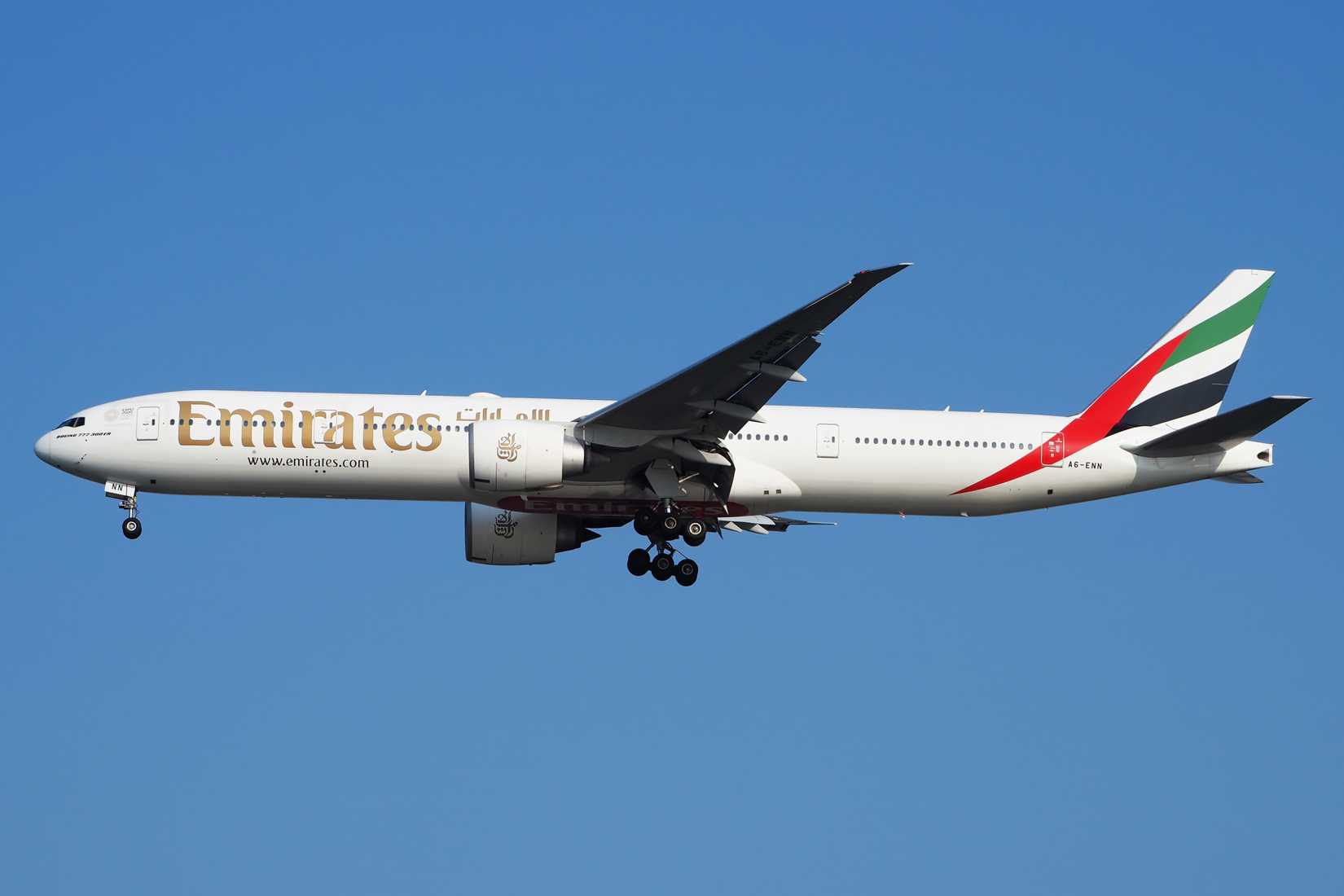Emirates 777-300 flying across clear skies