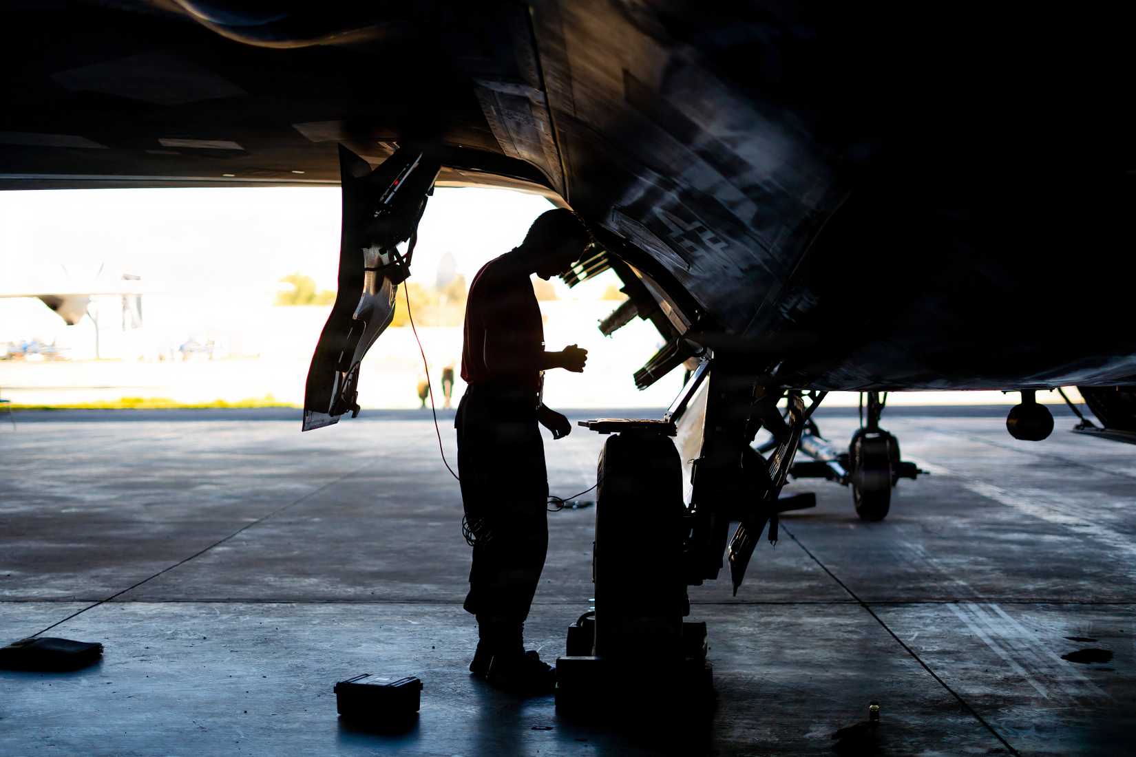 An F-22 undergoes maintenance in a hangar.
