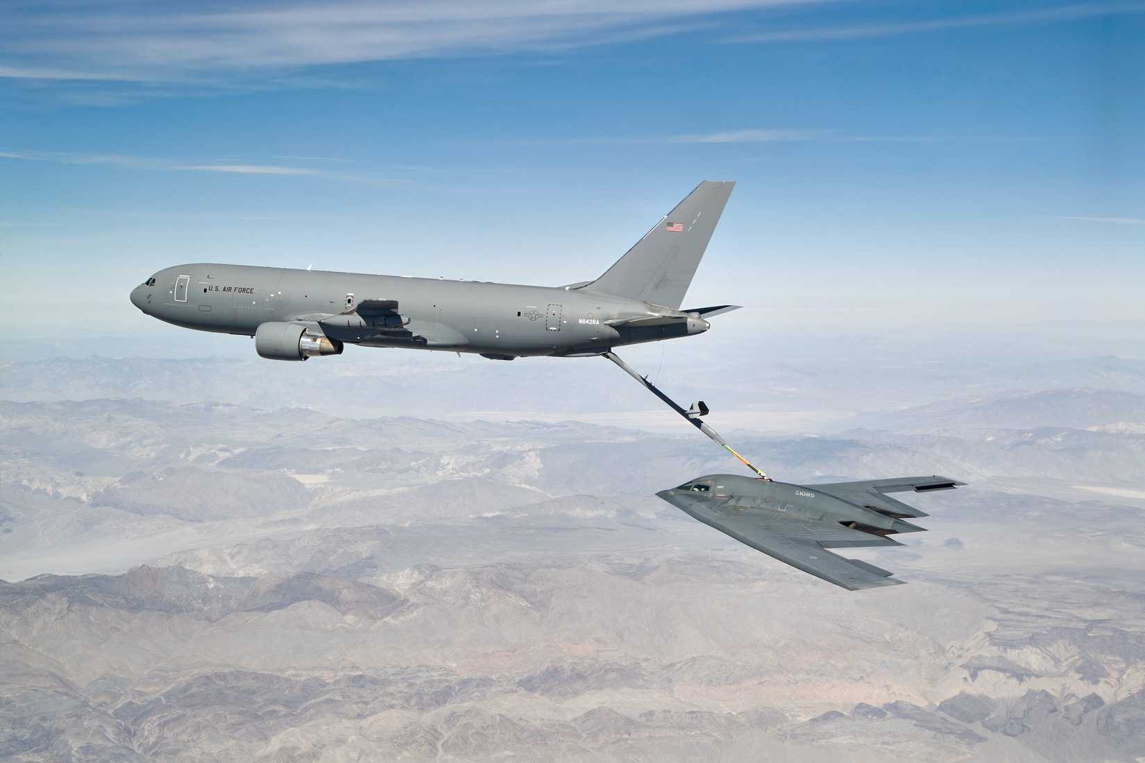 A photo of a KC-46 Refueling a B-2 above a mountain range