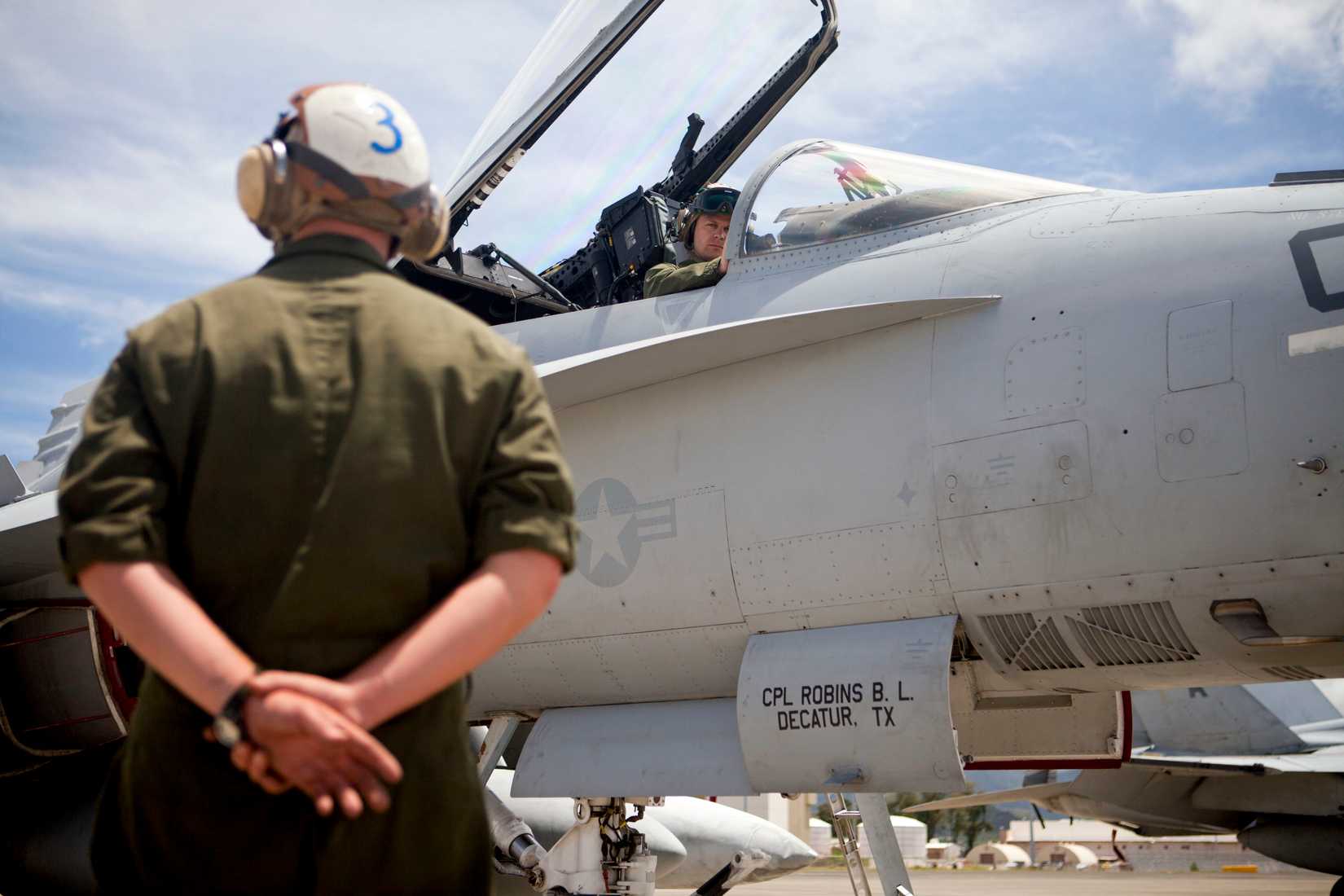 Marine Corps Major Benjamin A. Chamberlin, Pilot and Assistant Aircraft Maintenance Officer, waits for a signal from Sergeant Maximillia.