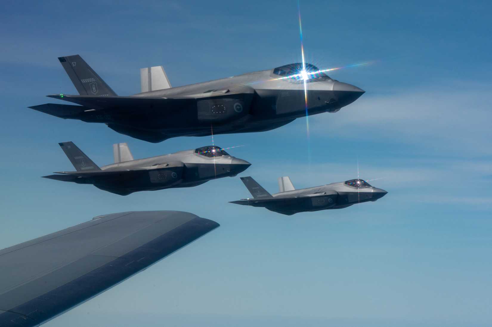 Royal Australian Air Force F-35A Lightning II aircraft fly alongside a U.S. Air Force KC-46 Pegasus aircraft.