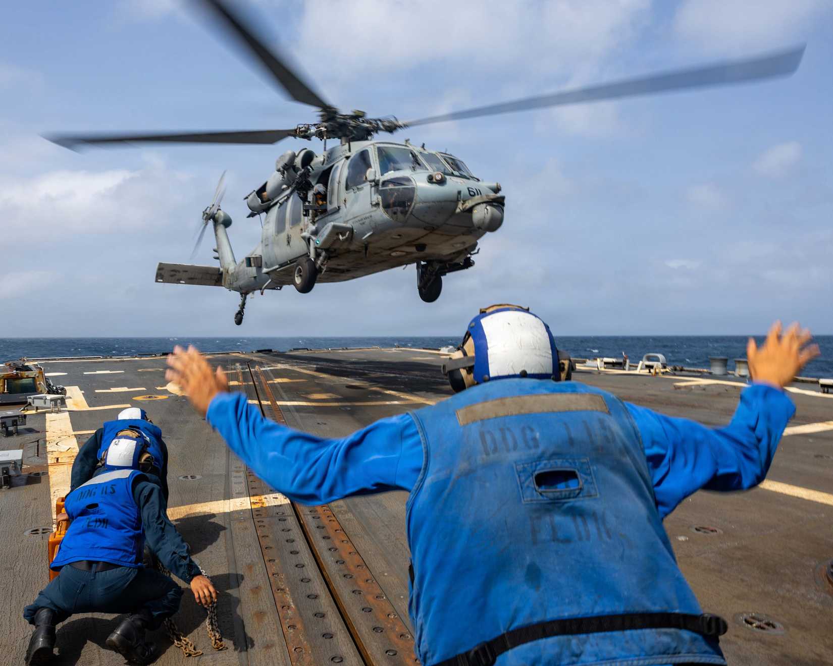 Sailor signals as an MH-60S Sea Hawk lands on the flight deck of Arleigh Burke-class guided-missile destroyer USS Rafael Peralta (DDG 115)-1