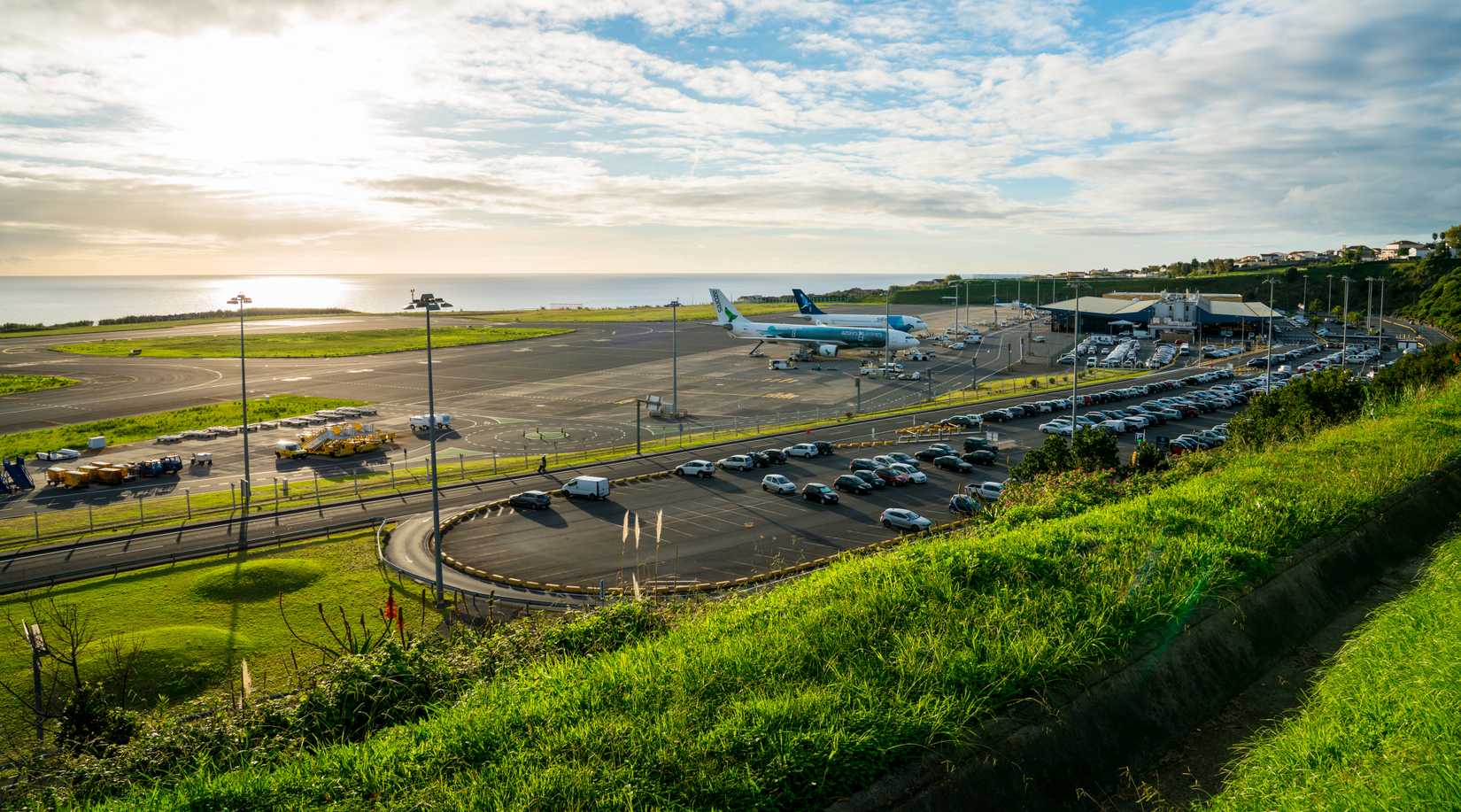  San Miguel, Azores. Aerial view on the airport with few planes parked by the terminal. Airport is located by the Atlantic ocean. Sunset time. 
