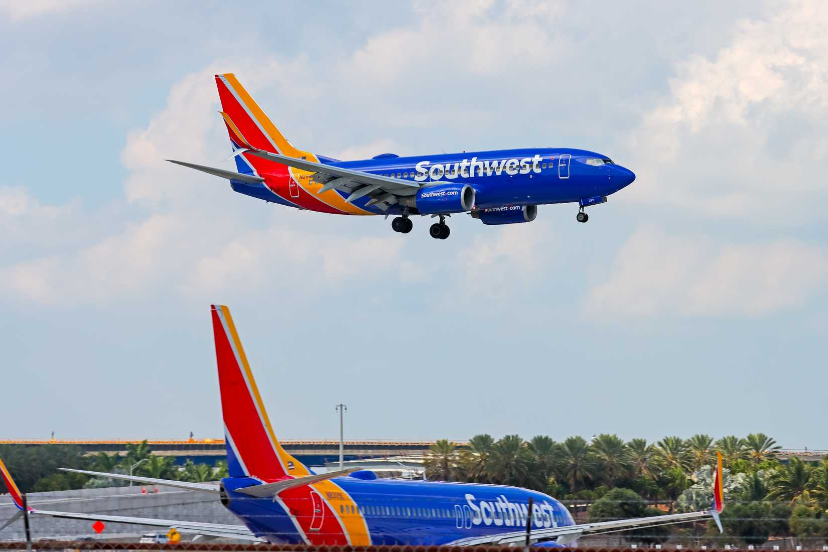 Southwest 737-700 landing while another Southwest 737 is waiting by the runways