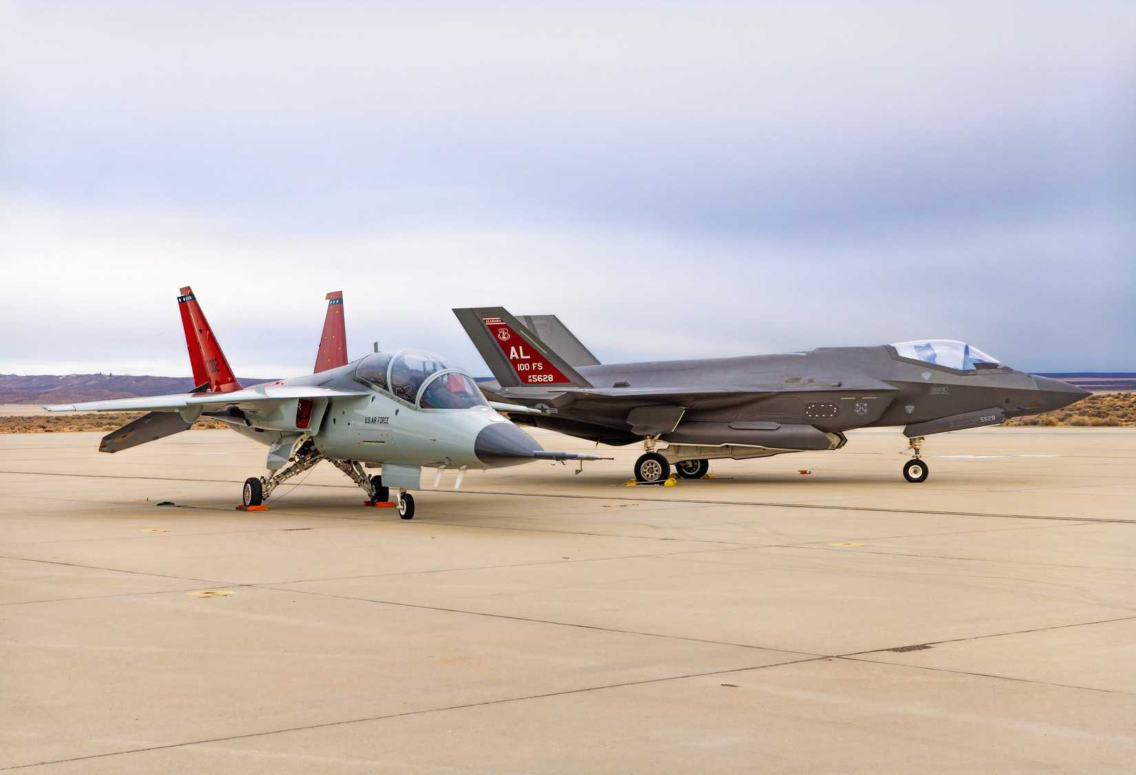 A photo of a T-7 Red Hawk parked next to an F-35 on an apron.